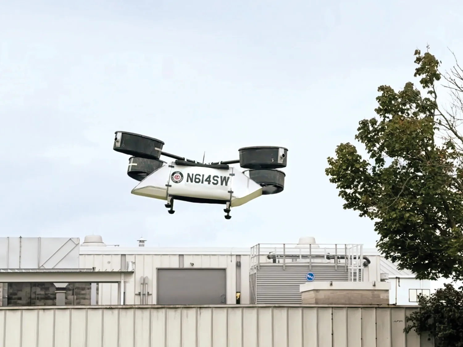 A model rescue drone created at Ohio State flies into the air. It has a large body to ferry people or supplies and 8 propellers enclosed in four cannisters, each at the end of a pole. Together, they're laid out as a helicopter's rotors would be.  