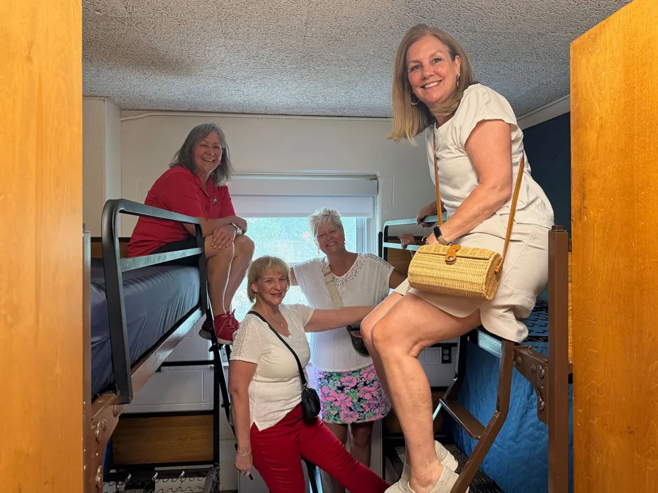 Molly Ranz Calhoun and three former dorm mates laugh as they crowd into a dorm room where they used to live. 