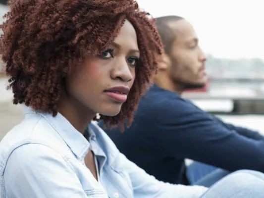 A man and woman both look into the distance, but away from each other