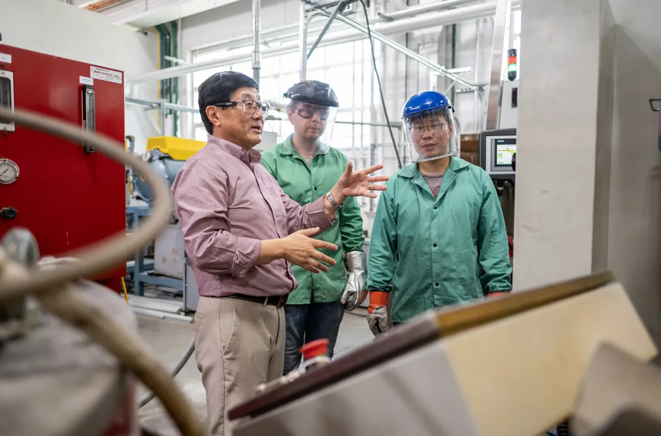 Alan Luo gestures as he works with grad students in his metals lab