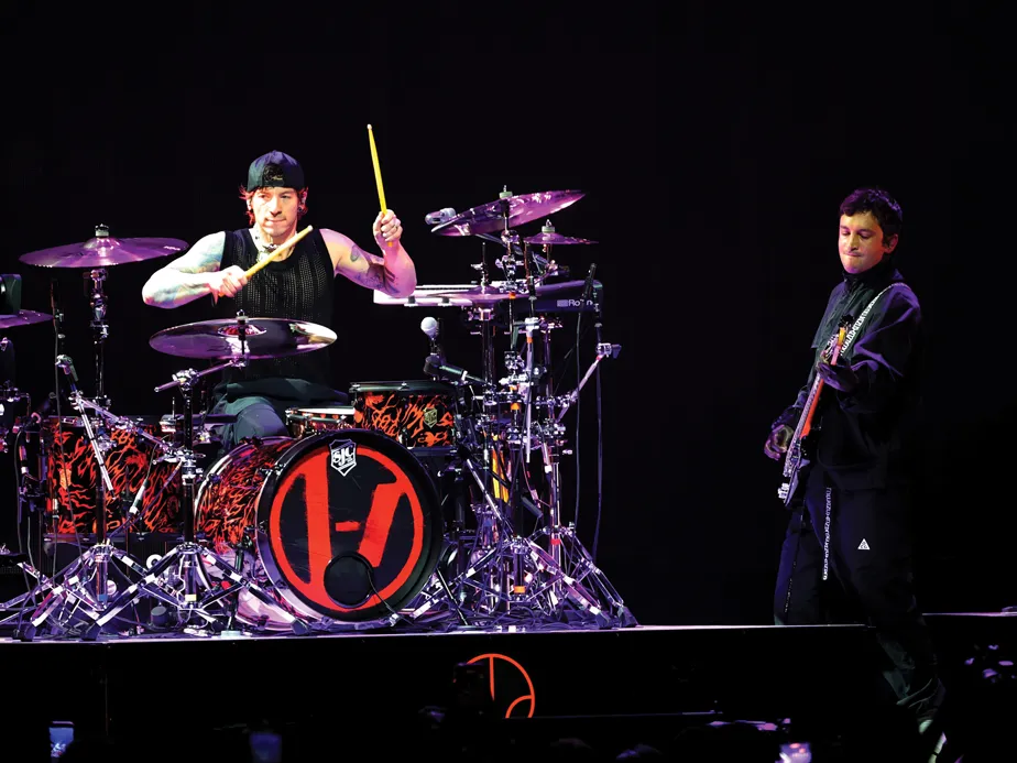 Two band members-a drummer and a guitarist-play on stage during a concert