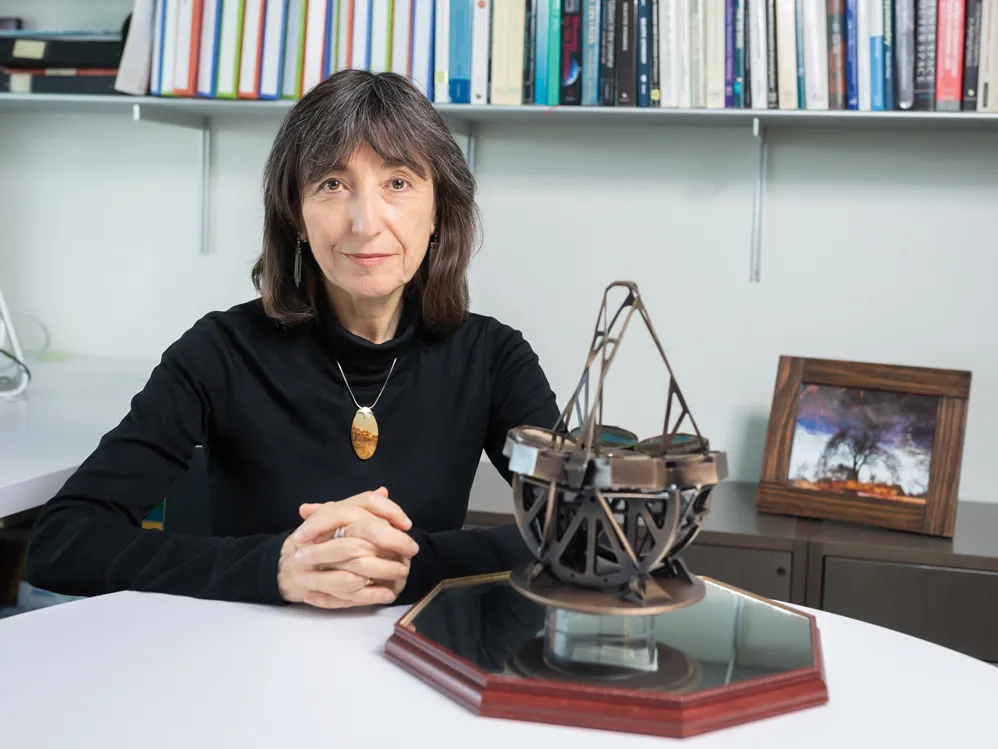 Wendy Freedman appears calm and knowing as she poses for a photo sitting at a desk in her office. A complicated-looking metal contraption sits on the desk near her.