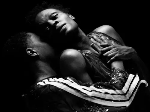 Two dancers hold each other in a dramatic black and white photo. 