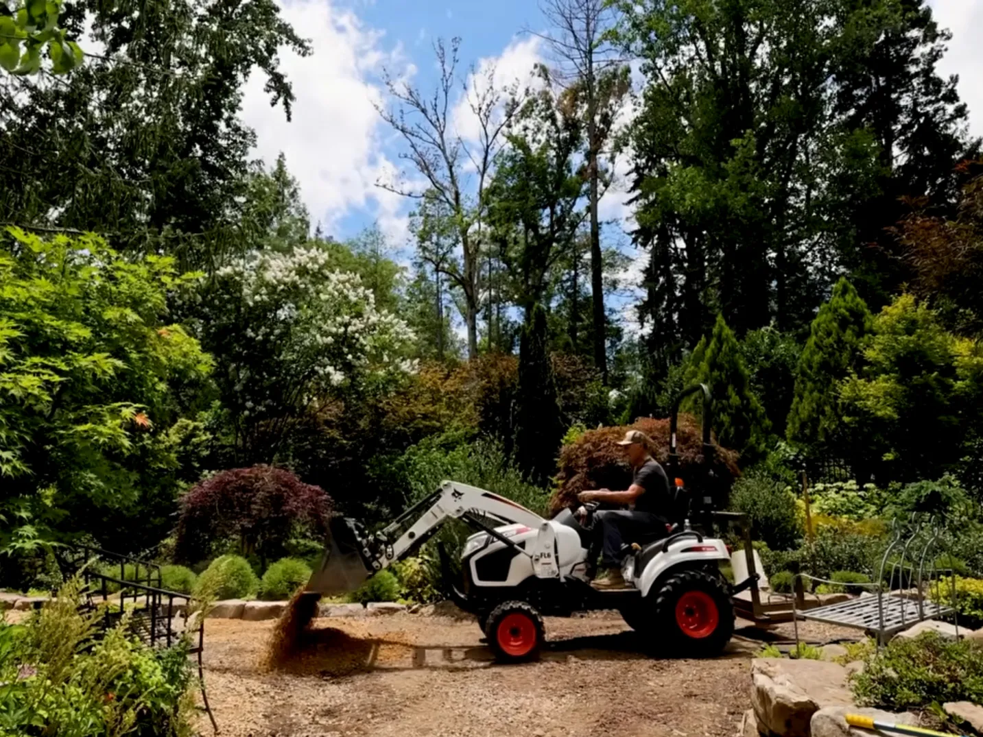 Hutchison drives a tractor along a trail in his garden