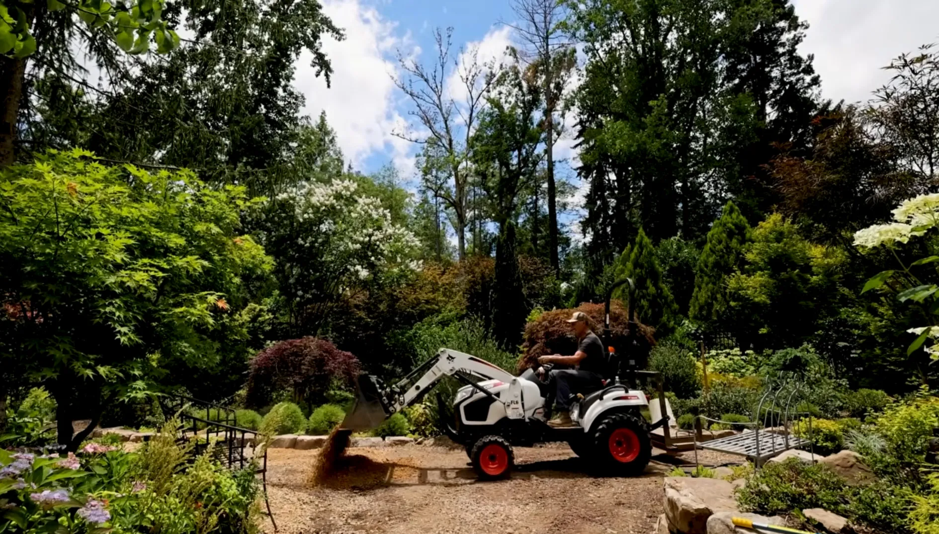 Hutchison drives a tractor along a trail in his garden