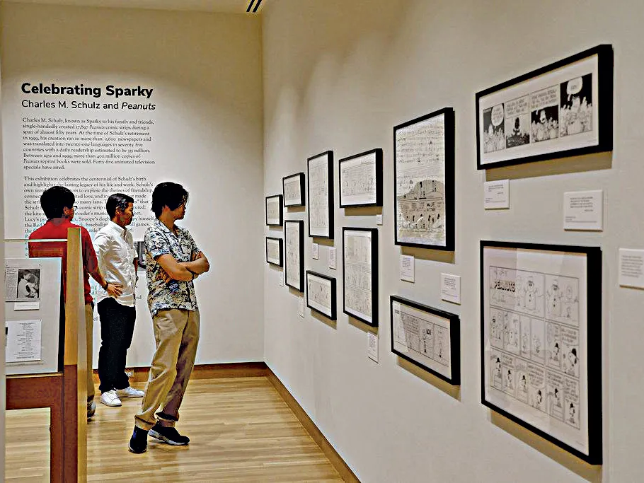 Museum visitors look at cartoons mounted on the walls of the Billy Ireland