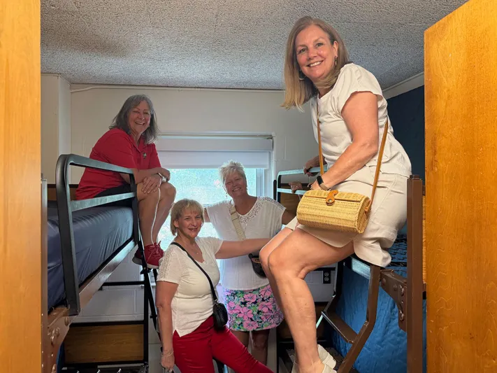 Molly Ranz Calhoun and three former dorm mates laugh as they crowd into a dorm room where they used to live. 