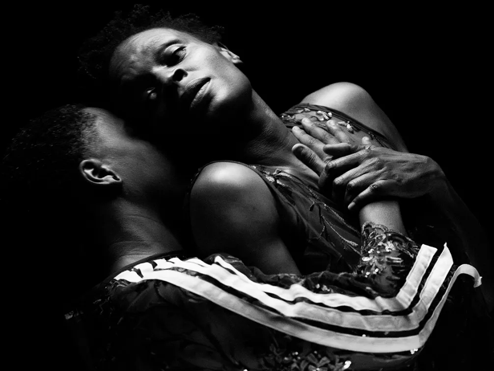 Two dancers hold each other in a dramatic black and white photo. 