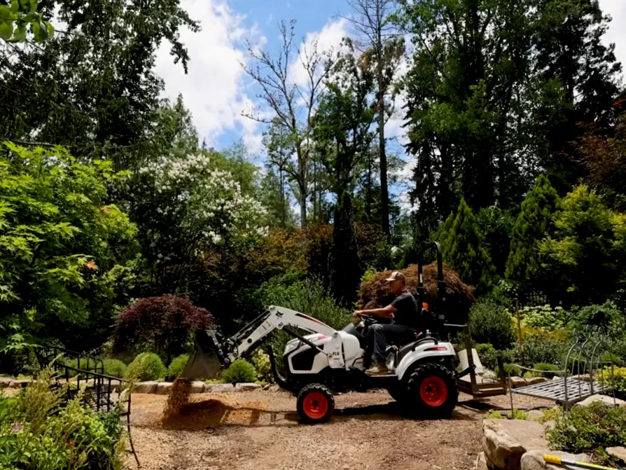 Hutchison drives a tractor along a trail in his garden