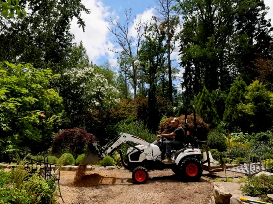 Hutchison drives a tractor along a trail in his garden