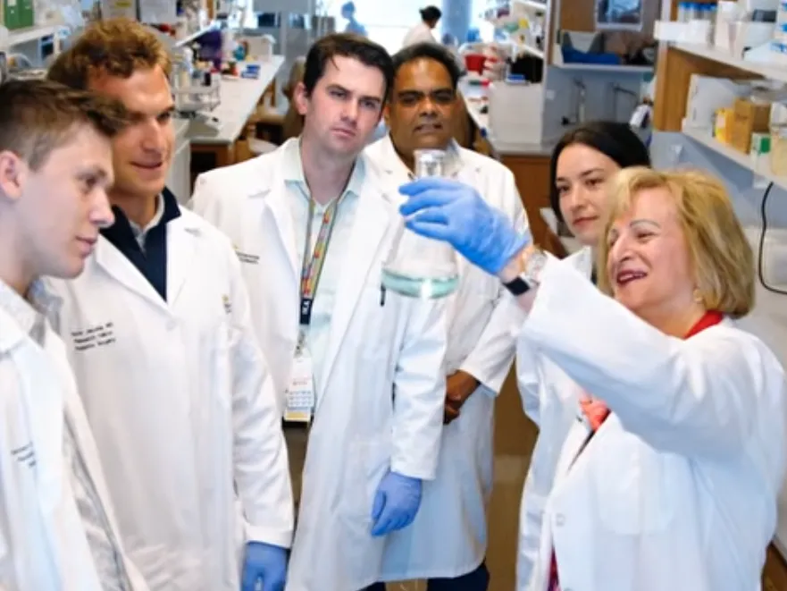 Dr. Gail Besner holds up a beaker, showing it to a group of her students