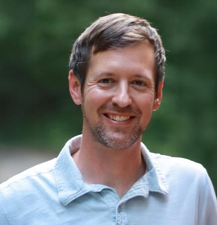 a smiling man looks directly at the camera